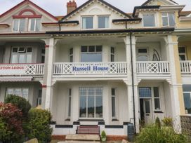 A white two-story building with a balcony and a sign that reads Russell House in Paignton