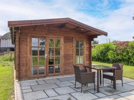 A wooden cabin with a table and chairs on a paved patio at Lodge 2 in York