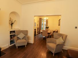 A living room with armchairs and a view into the dining area at 7 Lonsdale Terrace Penrith