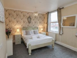 A bedroom with a bed, nightstand, and window at Bridlington Bay House in Bridlington