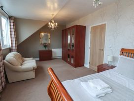 A bedroom with bed, armchair, wardrobe, and mirror at Bridlington Bay House in Bridlington