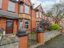 A row of red brick terraced houses with front gardens and iron gates at 6 Canning Road in Colwyn Bay