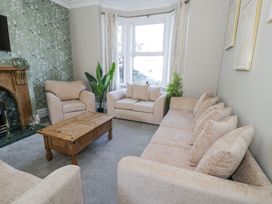 A living room with beige sofas wooden coffee table and a fireplace at 6 Canning Road Colwyn Bay