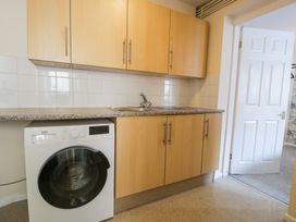 A kitchen with wooden cabinets a washing machine a sink and a white door open to another room at 6 Canning Road in Colwyn Bay