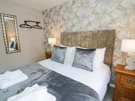A bedroom with a bed with grey pillows and blanket two bedside tables with lamps and a wall mirror at 6 Canning Road in Colwyn Bay