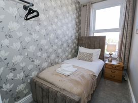 A bedroom with a single bed a bedside table lamp and patterned wallpaper at 6 Canning Road Colwyn Bay