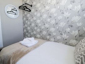 A bedroom with a bed folded towels a round mirror and hangers on wall at 6 Canning Road Colwyn Bay