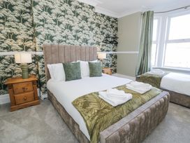 A bedroom with two beds green pillows bedside tables lamps and patterned wallpaper at 6 Canning Road Colwyn Bay