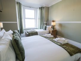 A bedroom with two beds a wooden nightstand and a window at 6 Canning Road Colwyn Bay