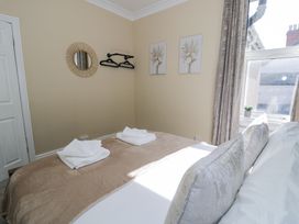 A bedroom with a bed folded towels wall hangers and a window at 6 Canning Road in Colwyn Bay