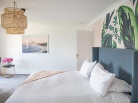 A bedroom with a bed and wall art at Newquay Tamarisk Lodge on the Gannel Newquay