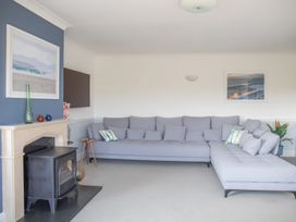 A living room with a gray sofa and fireplace at Newquay Tamarisk Lodge on the Gannel in Newquay