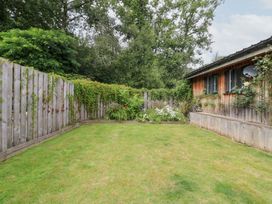 A garden with grass and a flower bed at Gloccamaura in Bovey Tracey