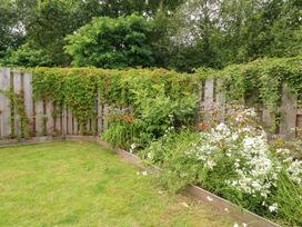 A garden with grass and flower beds at Gloccamaura in Bovey Tracey