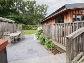 An outdoor patio area with a wooden table and chairs at Gloccamaura in Bovey Tracey