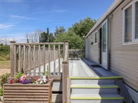 An outdoor area with decking, steps, a door, and a table with chairs at The Hideaway in Portesham