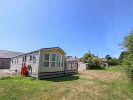 A mobile home with a deck and nearby house at The Hideaway in Portesham
