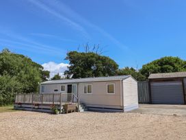 A mobile home in a gravel area with trees at The Hideaway in Portesham