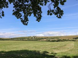 A field with trees and hills under a clear sky at The Hideaway in Portesham