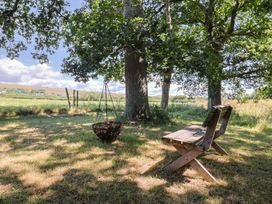 A grassy area with a wooden chair and a swing hanging from a tree at The Hideaway in Portesham