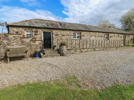 A stone cottage with a bench and flower pots at Rainbow Cottage in Kirkby Stephen