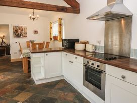 A kitchen with appliances and a dining table at Rainbow Cottage in Kirkby Stephen