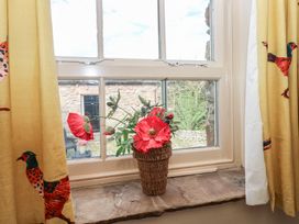 A window with a flower arrangement on the sill at Rainbow Cottage in Kirkby Stephen