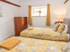 A bedroom with two beds and a window at Rainbow Cottage in Kirkby Stephen