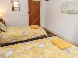 A bedroom with two beds and a wooden door at Rainbow Cottage in Kirkby Stephen