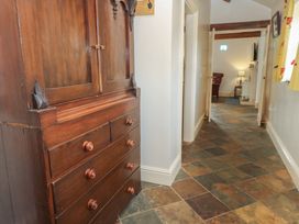 A hallway with an armoire and light at Rainbow Cottage in Kirkby Stephen