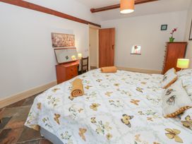 A bedroom with a large bed and wooden furniture at Rainbow Cottage in Kirkby Stephen
