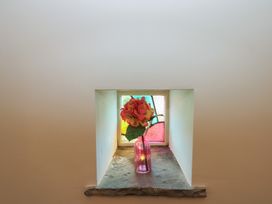 A flower in a vase on a stone ledge near stained glass at Rainbow Cottage in Kirkby Stephen