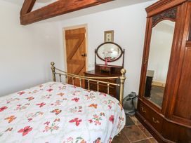 A bedroom with a bed, dresser, and wardrobe at Rainbow Cottage in Kirkby Stephen