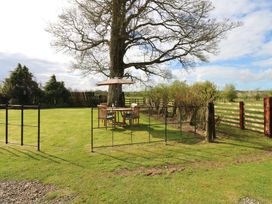 A garden with a table and chairs under a parasol at Rainbow Cottage in Kirkby Stephen