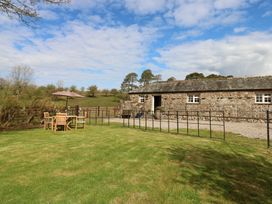A garden with table and chairs beside a stone building at Rainbow Cottage in Kirkby Stephen