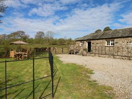 A table and chairs under a parasol outside a barn at Rainbow Cottage in Kirkby Stephen