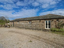 A stone building with double doors and a gravel driveway at Rainbow Cottage in Kirkby Stephen