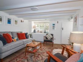 A living room with a sofa, armchair, and coffee table at Ivy Cottage in Trenale near Tintagel
