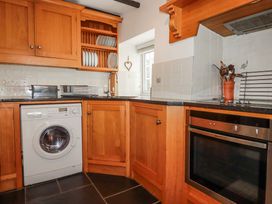 A kitchen with wooden cabinets and appliances at Ivy Cottage in Trenale near Tintagel