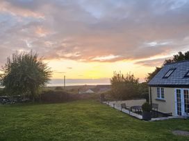 A garden with a house and table at Ivy Cottage in Trenale near Tintagel