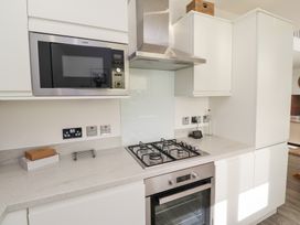 A kitchen with microwave, oven, and gas hob at The Beach House (Beadnell)