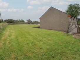 A garden area with grass and a building at Bryn Caled in Llanarmon near Y Ffor