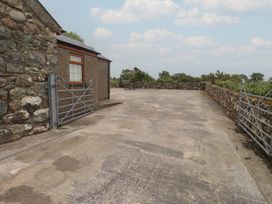 A concrete area with a gate and stone wall at Bryn Caled in Llanarmon near Y Ffor