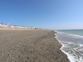 A beach with a sea lapping at the shore and buildings in the background at Bryn Caled Llanarmon near Y Ffor