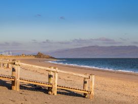 A beach with a wooden boardwalk and mountains in the background at Bryn Caled in Llanarmon near Y Ffor