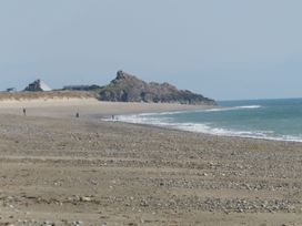 A beach with people in the distance and rocks at Bryn Caled Llanarmon near Y Ffor