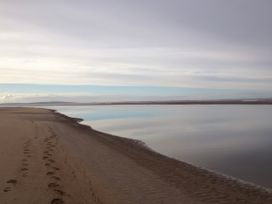 A beach with footprints leading to a calm water at Geesala in Gweesalia