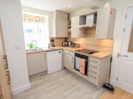 A kitchen with a sink under a window and an electric stove with oven at 4 Martindales Yard in Kendal