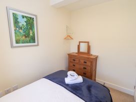 A bedroom with a bed, dresser with a mirror, wall art, and a clothes hanger at 4 Martindales Yard in Kendal