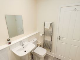 A bathroom with a sink a toilet a mirror a chrome towel rail with a towel and a white door at 4 Martindales Yard in Kendal